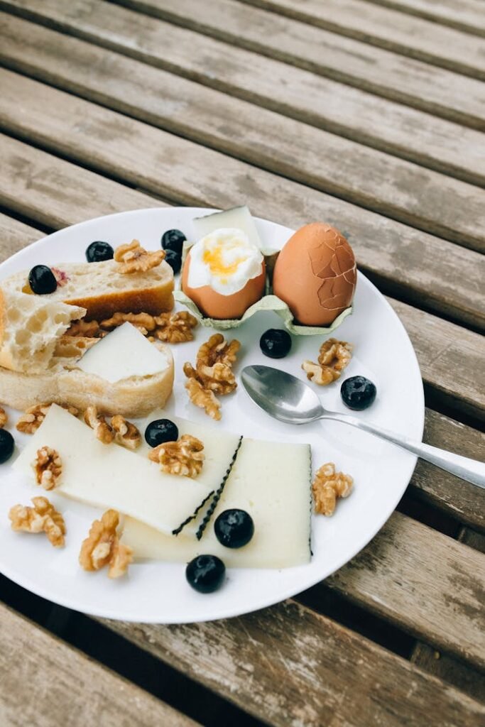 A rustic breakfast plate with cheese, walnuts, eggs, and blueberries on a wooden table.